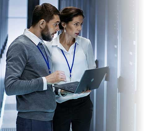 Man and woman in server room looking at a laptop