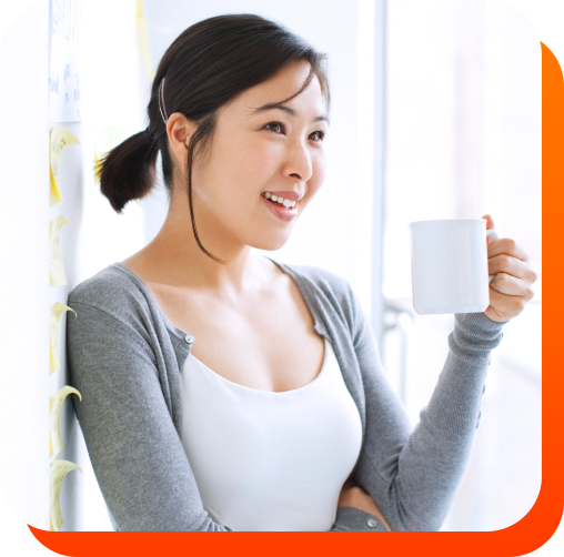 smiling female leaning on a wall with a mug in her hand