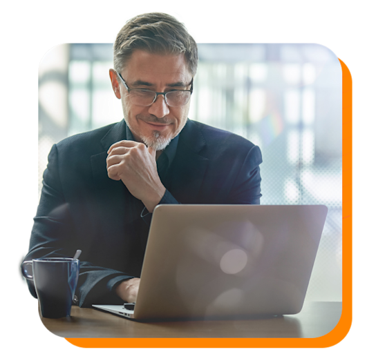 Man smiling down at his laptop with a coffee mug on the desk
